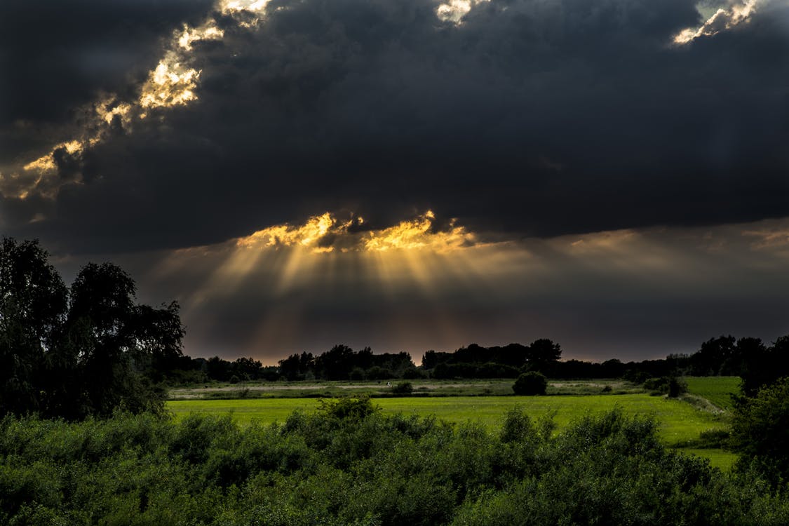 Storm over a field - sunlight cracking through clouds